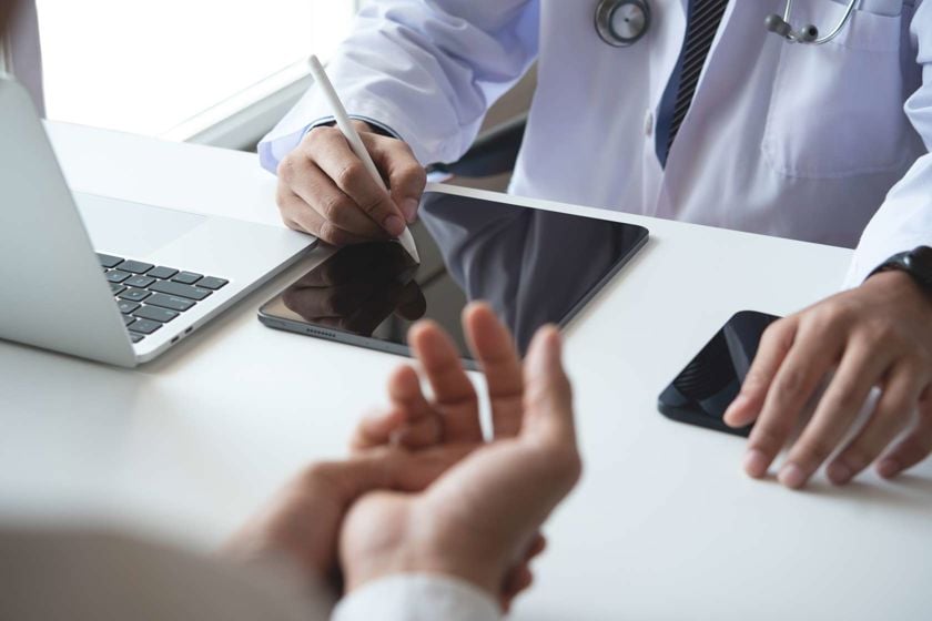 Medical Professional Recording Patient Information On Tablet 