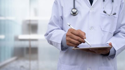 Close Up Of Doctor Writing On Tablet 