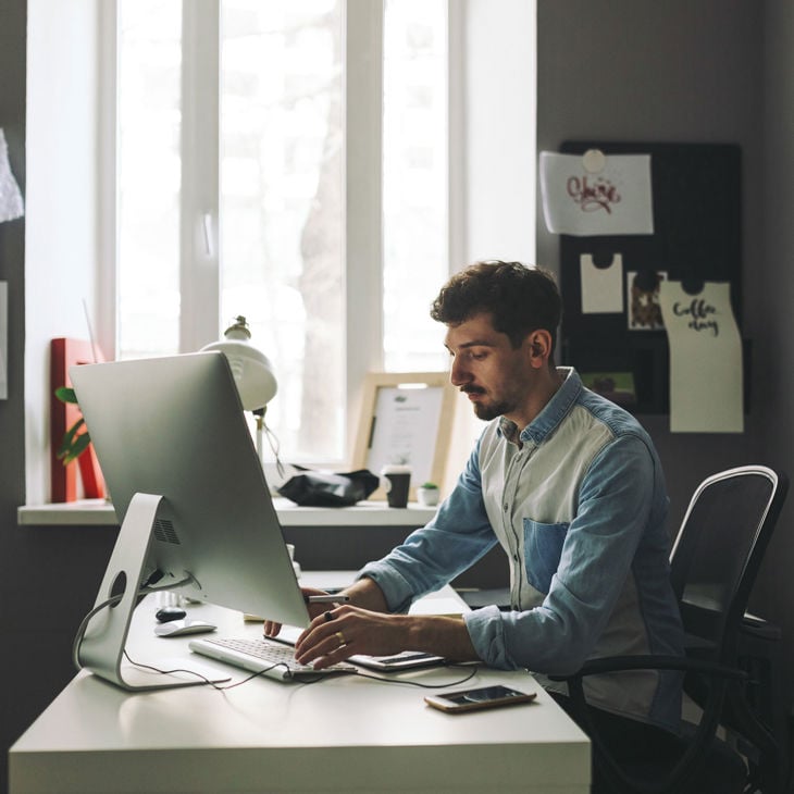 Person Typing On Desktop Computer In Home Office 