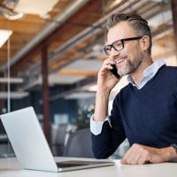 Person On Phone Smiling Over Laptop 