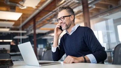 Person On Phone Smiling Over Laptop 