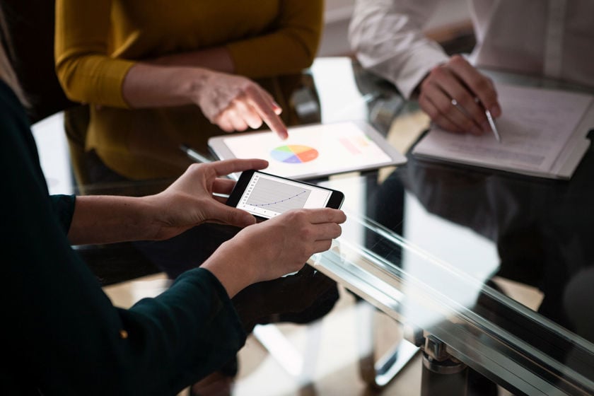Close Up Of Colleagues Reviewing Data On Phone 
