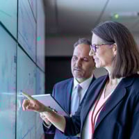 Colleagues Discussing Data On Wall Of Screens 