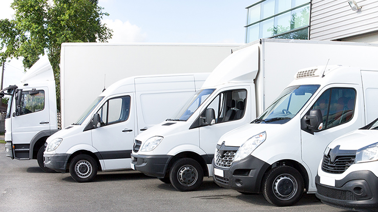 A staggered line of various white commercial vehicles.