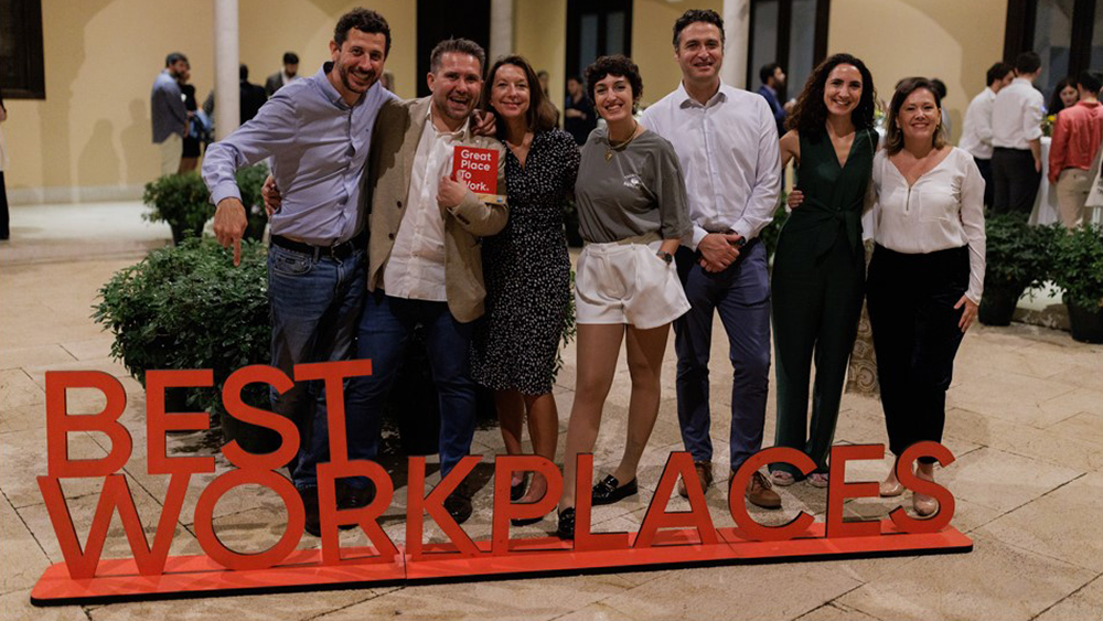Employees next to Best Workplaces sign