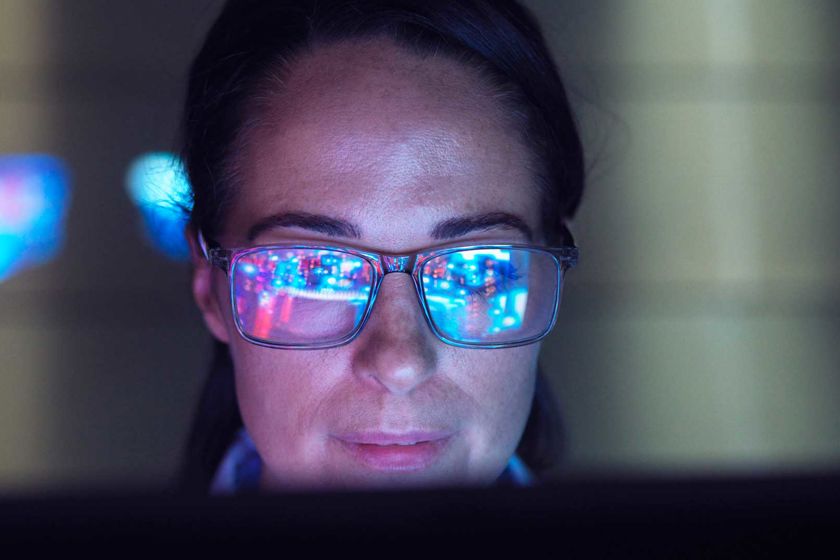 Woman Reviewing Data With Reflection In Glasses 