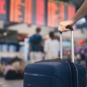 Hand Holding Suitcase In Airport Terminal 