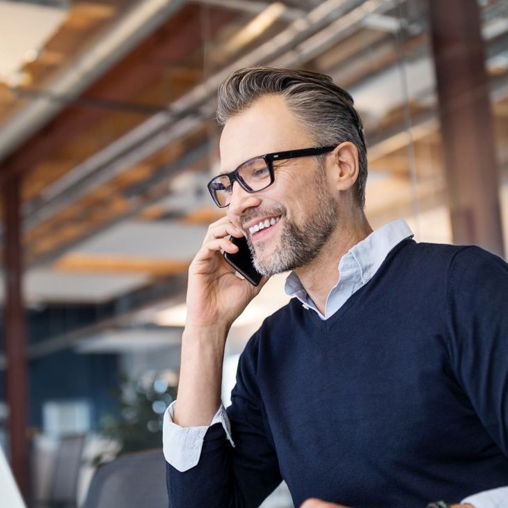 Man Talking On Mobile Looking At Laptop 