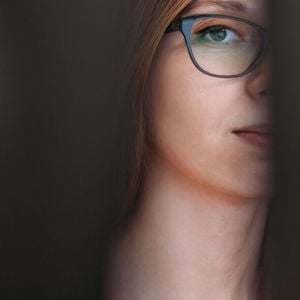 Woman Peering Between Two Computer Monitors 