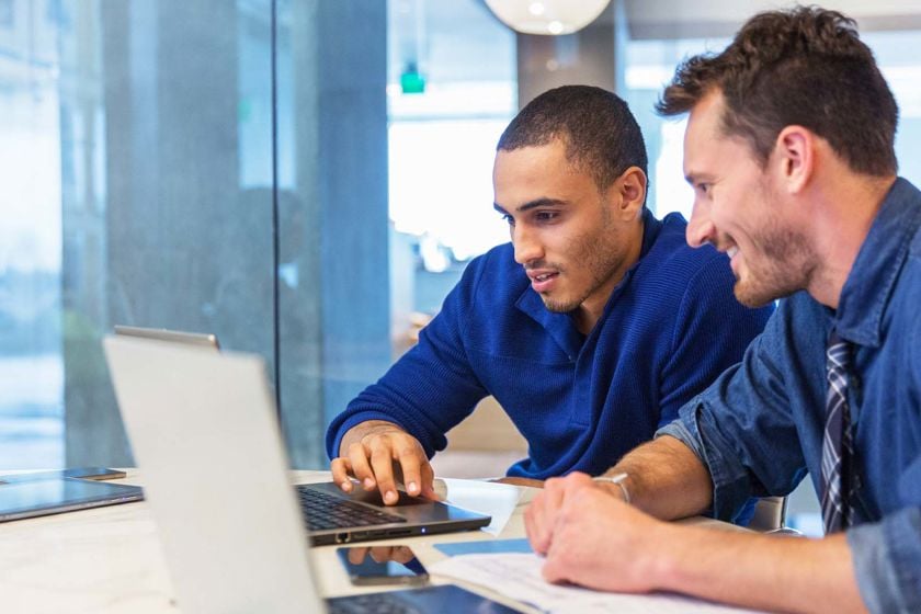 Two Men Reviewing Documents On Laptop 