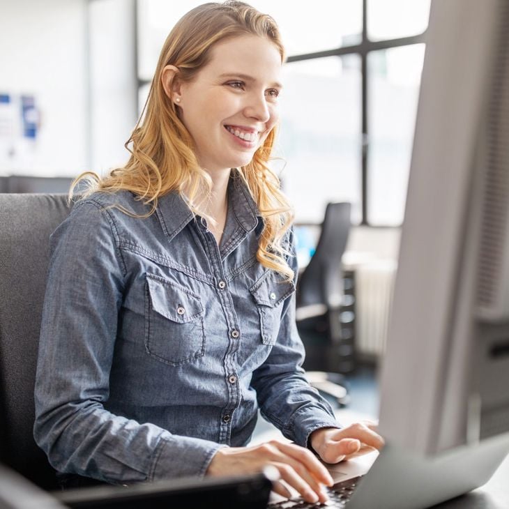 Smiling Woman Typing On Computer