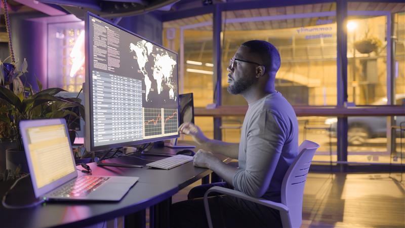 Man In Office Looking At Global Data On Computer Screen 