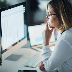 Woman Reviewing Data On Desktop Computer 