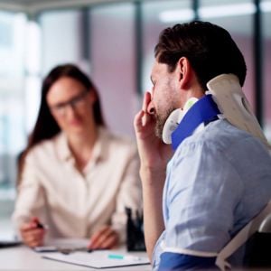 Man Stressed Wearing Neck Brace At Desk 