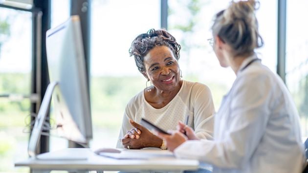 Women Sitting At Desk Talking 