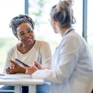 Women Sitting At Desk Talking 
