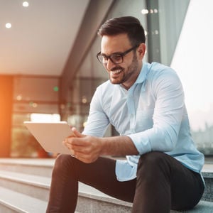 Smiling Individual Looking At Tablet 