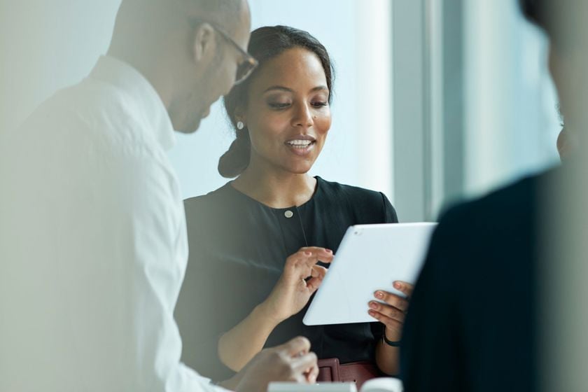 Woman Refering To Tablet Talking To Male Coworker 