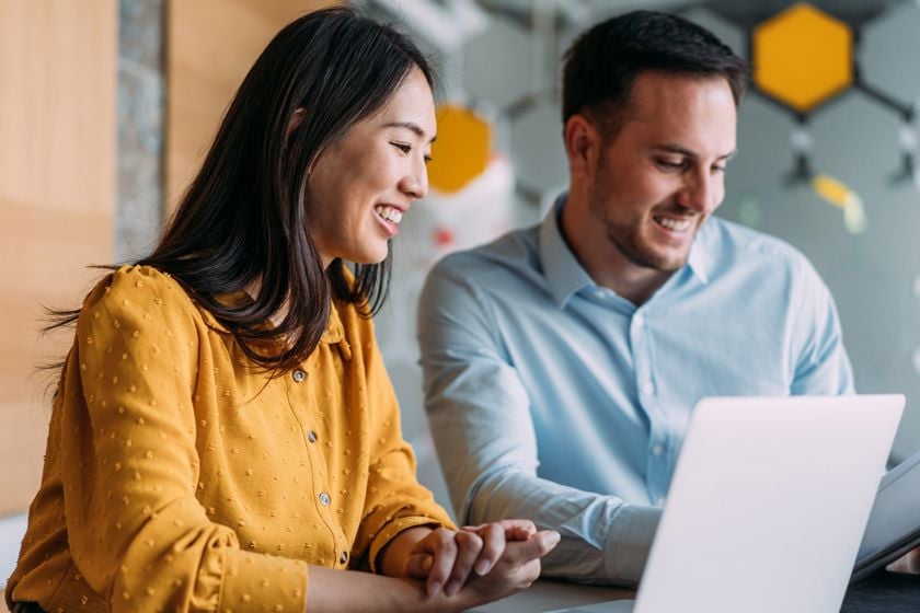 Coworkers Seated Smiling While Reviewing Documents 