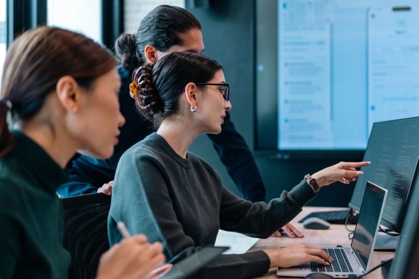 Trio Of People Reviewing Data On Computer Monitor 