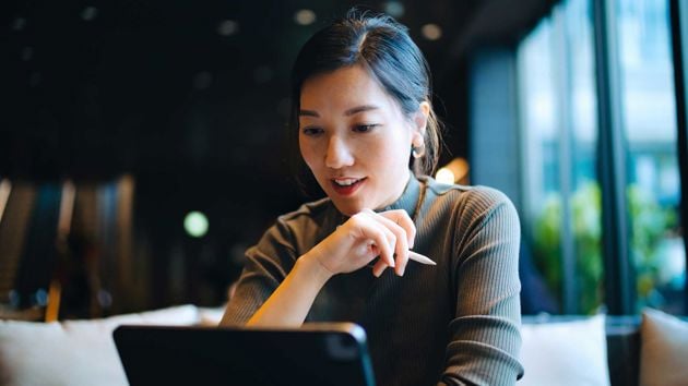Woman Reviewing Data On Tablet Holding Pen 