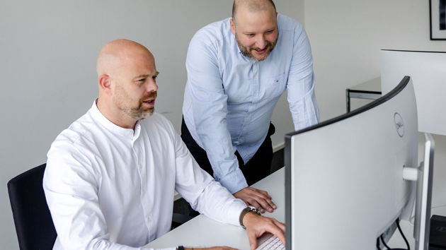 Colleagues Reviewing Data On Computer Monitor 