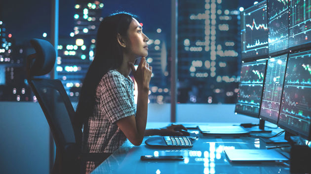 Woman Reviewing 6 Monitors Of Data 