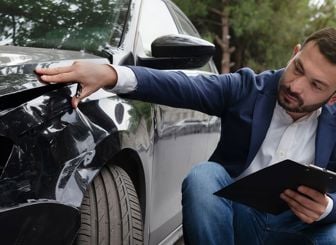 Adjuster Reviewing Damage To Car Fender 