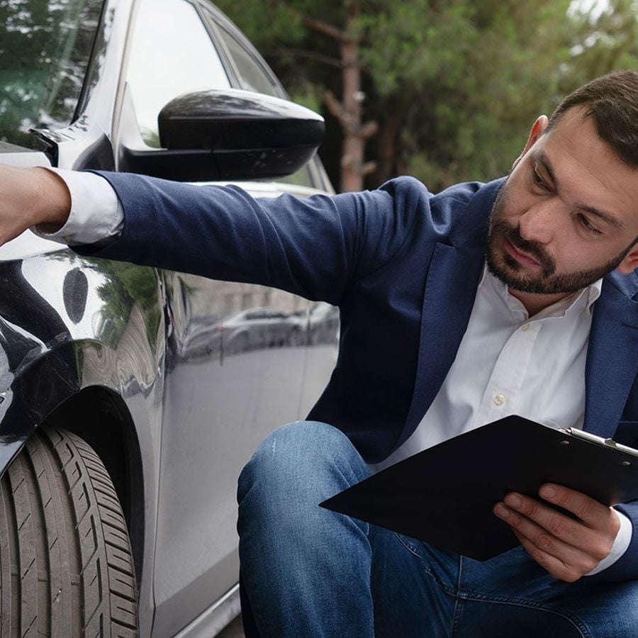 Adjuster Reviewing Damage To Car Fender 