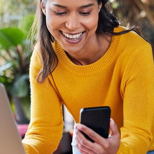 Person Smiling At Phone Over Laptop 
