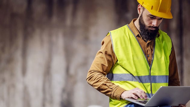 Construction Worker In Viewing Laptop At Jobsite 