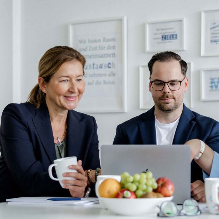 Three People At A Table Reviewing Information On A Laptop 