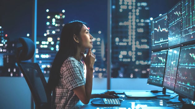 Woman Reviewing 6 Monitors Of Data 