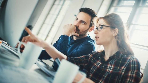 Man And Woman Reviewing Information On Monitor 