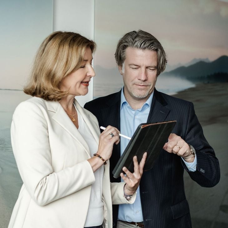 Standing Man And Woman Reading From A Tablet 