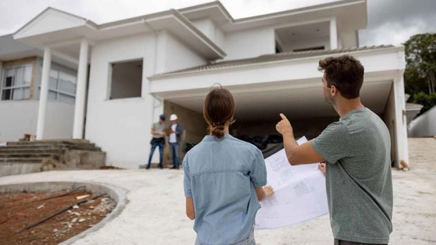 Man And Woman Looking At House Under Construction 