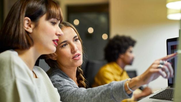 Two Women Reviewing Information On A Computer Monitor 