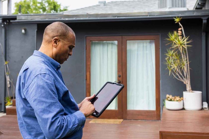 Man Standing On Outdoor Patio With Tablet 