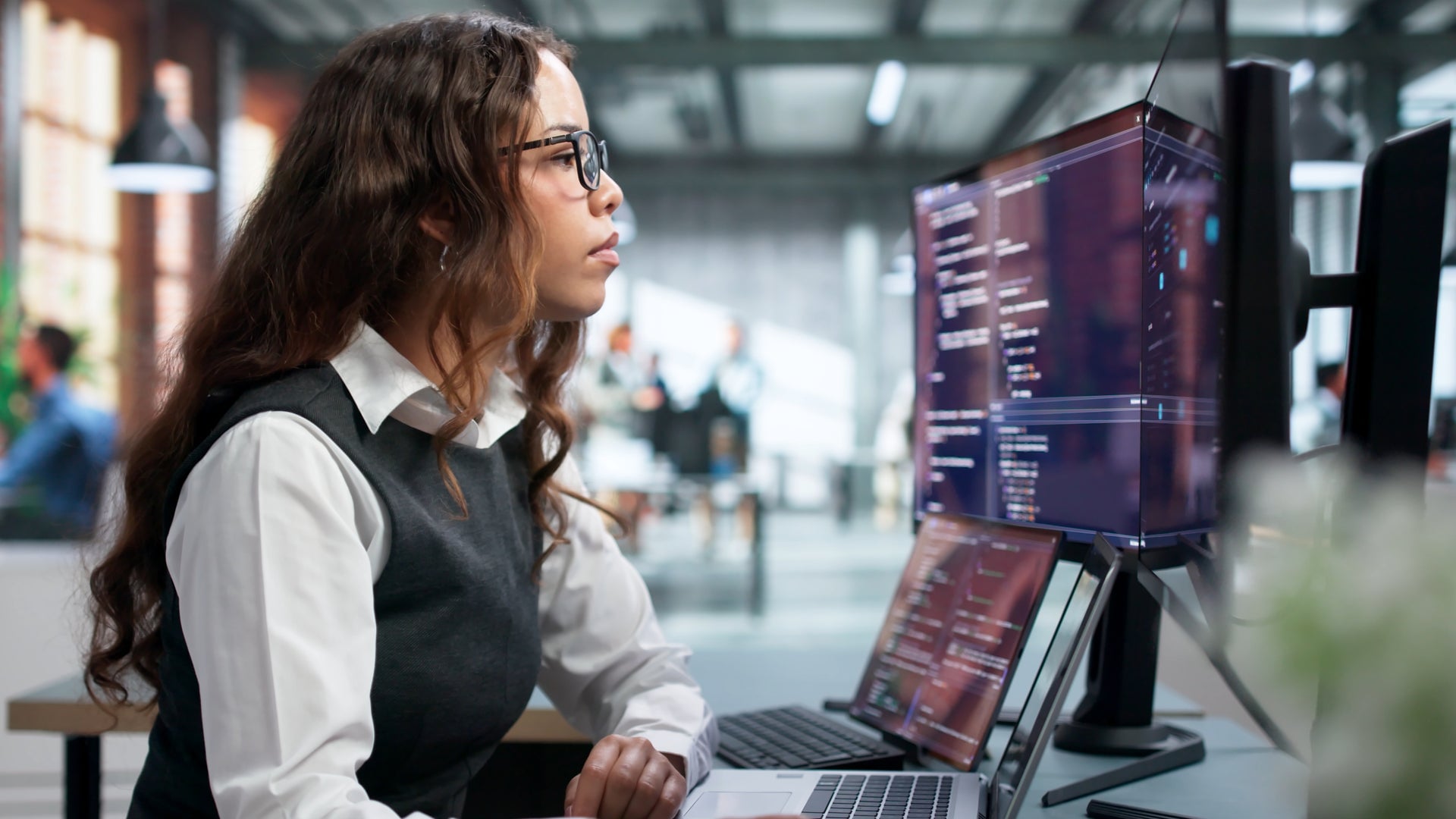 woman looking at laptop and external monitor