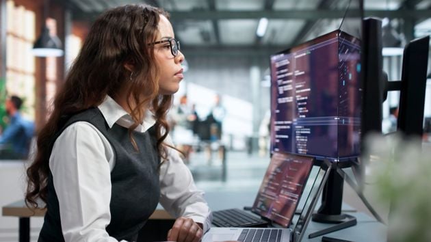 Woman Looking At Laptop And External Monitor 