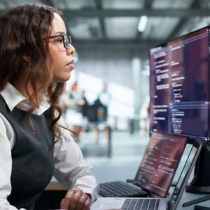Woman Looking At Laptop And External Monitor 