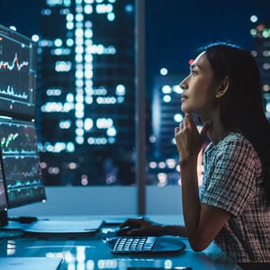 Woman Reviewing Data On An Array Of Monitors 