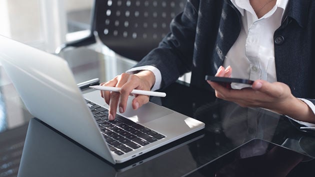 Person Using Laptop And Phone 