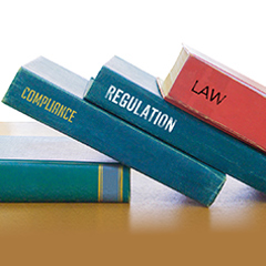 Spines of three books reading "Compliance," "Regulation," and "Law"