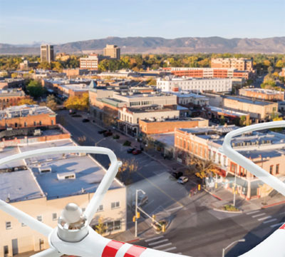 An unmanned aerial system collects photos and videos as it flies over a city.